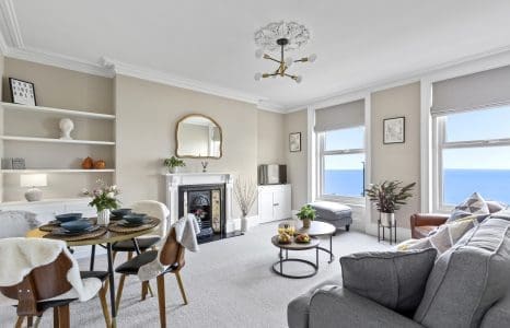 An image of a flat in Kent, you can see the sea just outside of the window. This is rented out for short-term rental or long-term rental by the property owner. The apartment is bright and spacious with a lounge filled with neutral but cosy tones.